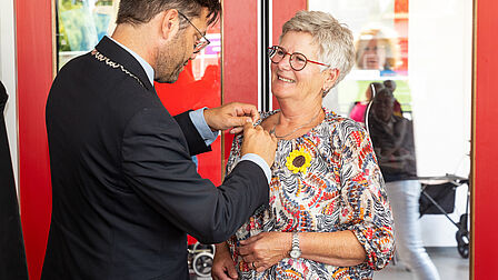 Mevrouw Stam-Delamarre krijgt een waarderingsspeld opgespeld door burgemeester Michiel Pijl. Deze foto is gemaakt door Pieter Prins.